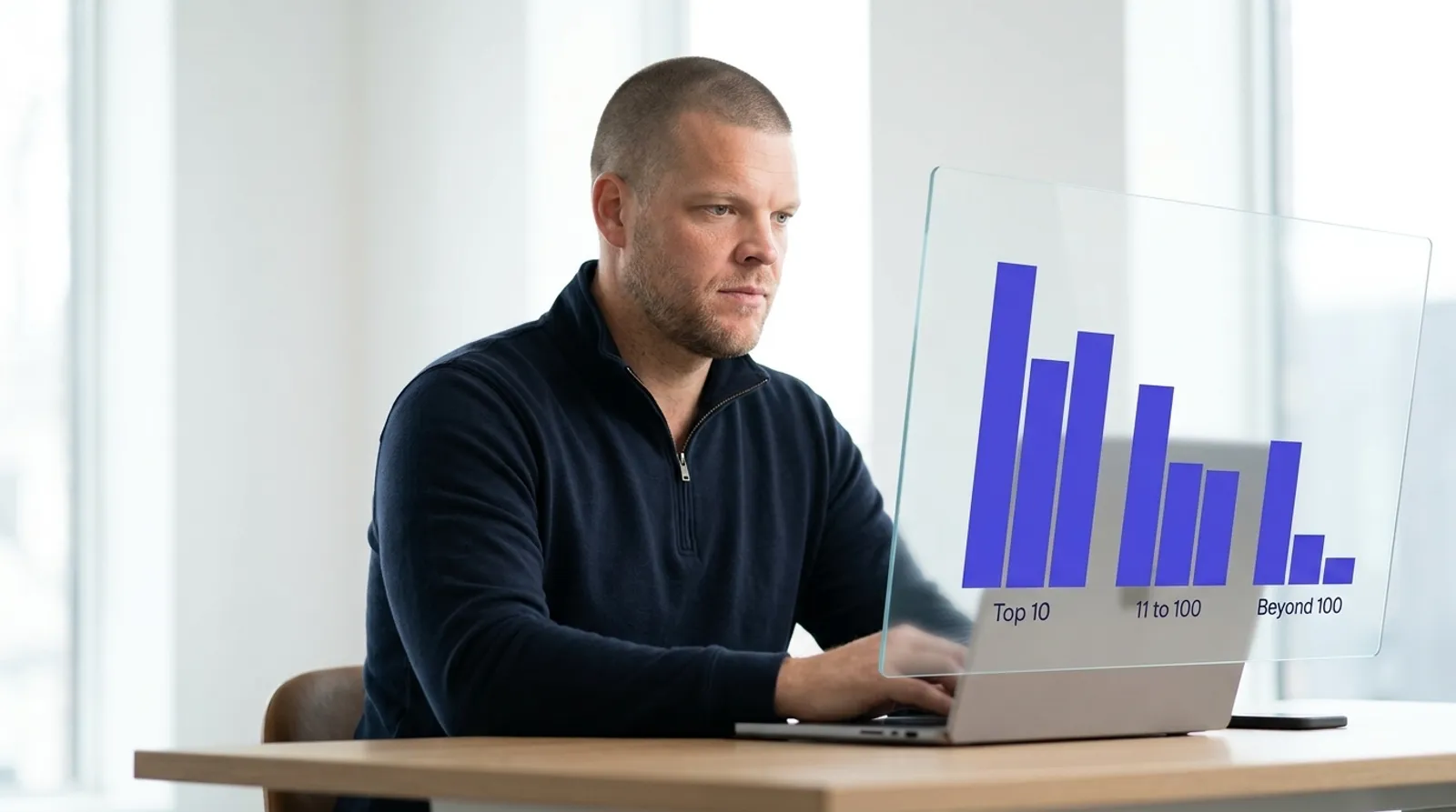 A man at a desk looking at a laptop, with a translucent glass panel beside it showing a bar chart of three bars labeled Top 10, 11 to 100, and Beyond 100, representing where AI Overview citations actually come from
