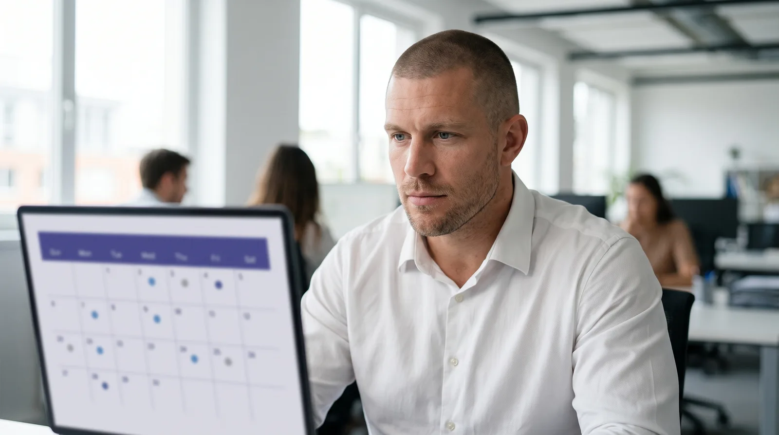 Mike Moore, founder of Strategic AI Architects, reviewing a content publishing calendar on a laptop screen in an office, checking which blog posts are recent and which have gone stale